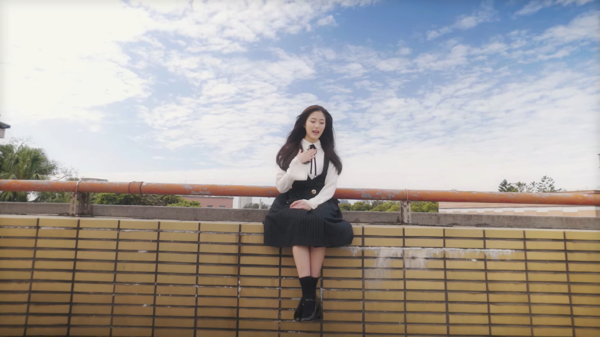 Hyunjin sitting in front of a blue sky.